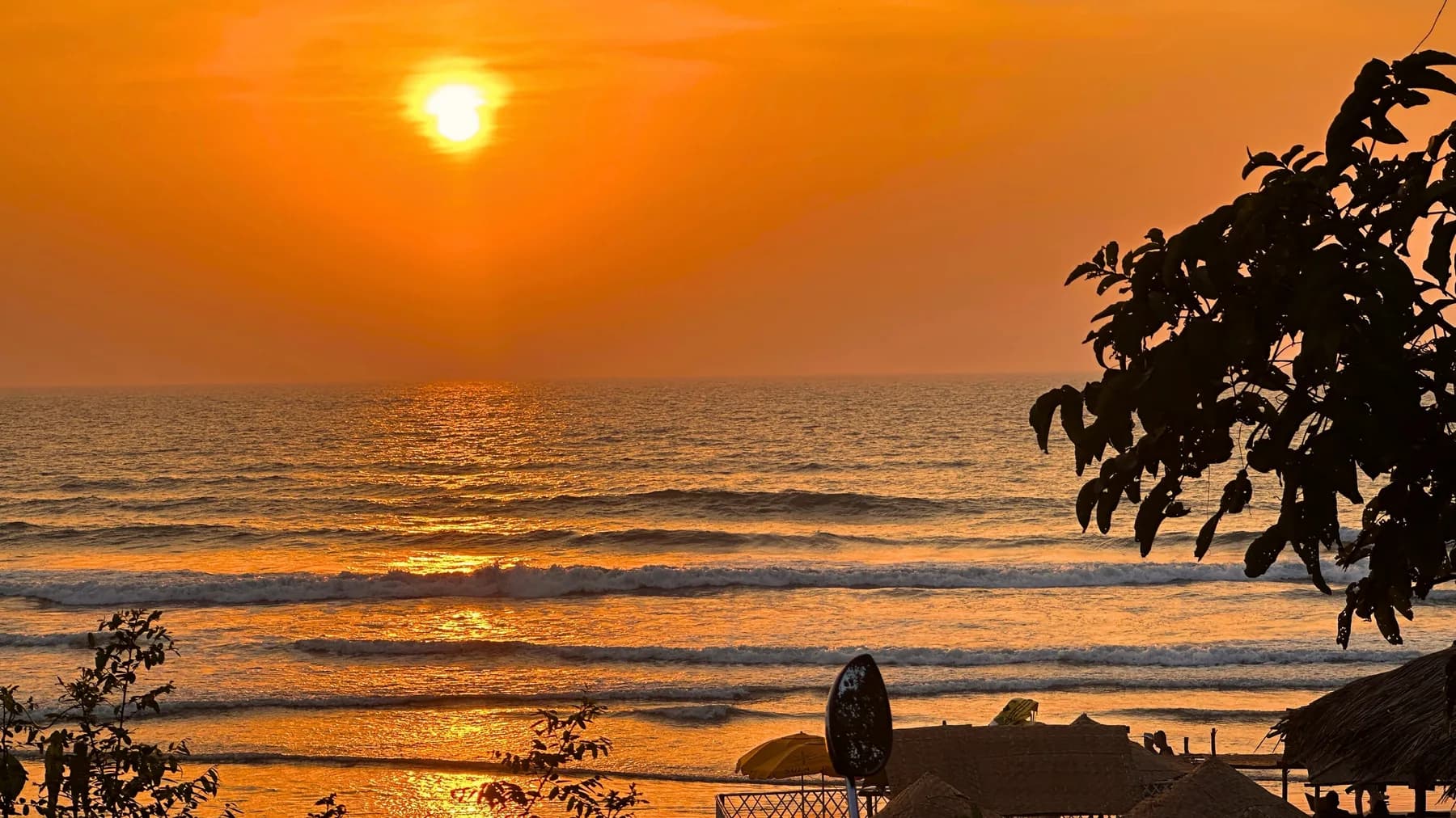 Sunset over the beach near Dharamkot Studio Goa with waves and orange coastal sky.